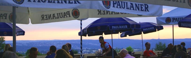 Paulaner Biergarten des Restaurant Zeus mit Paulaner-Schirmen und Panoramablick über Esslingen bei Sonnenuntergang